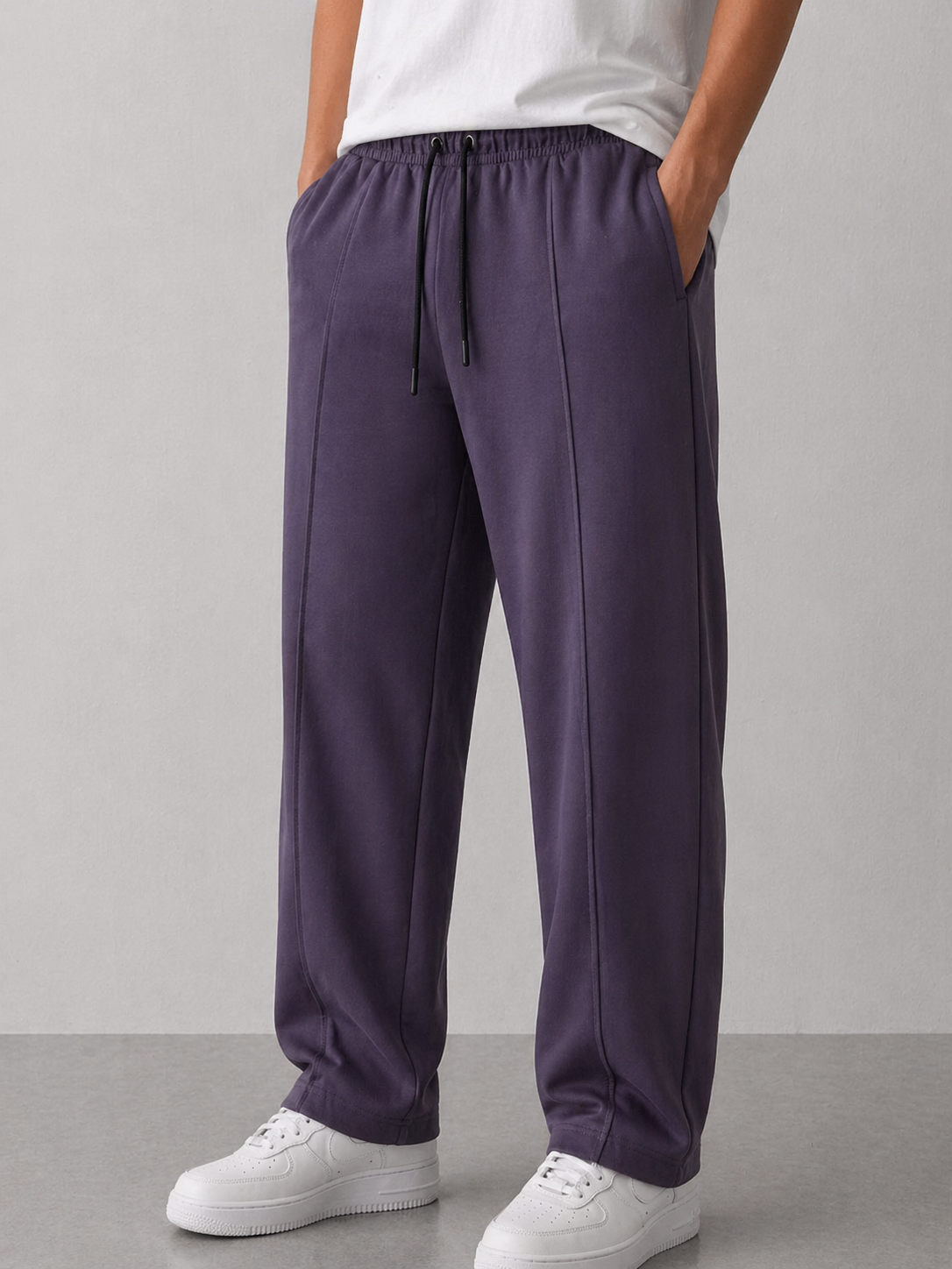 Person wearing purple pants and white shoes on a gray background