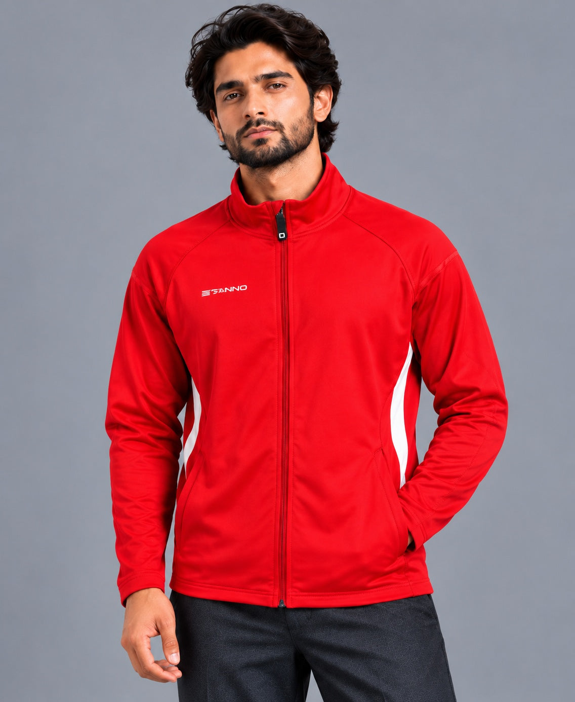 A man wearing a bright red athletic zip-up jacket with white side stripes and a small white logo on the left chest, photographed against a plain gray studio background.